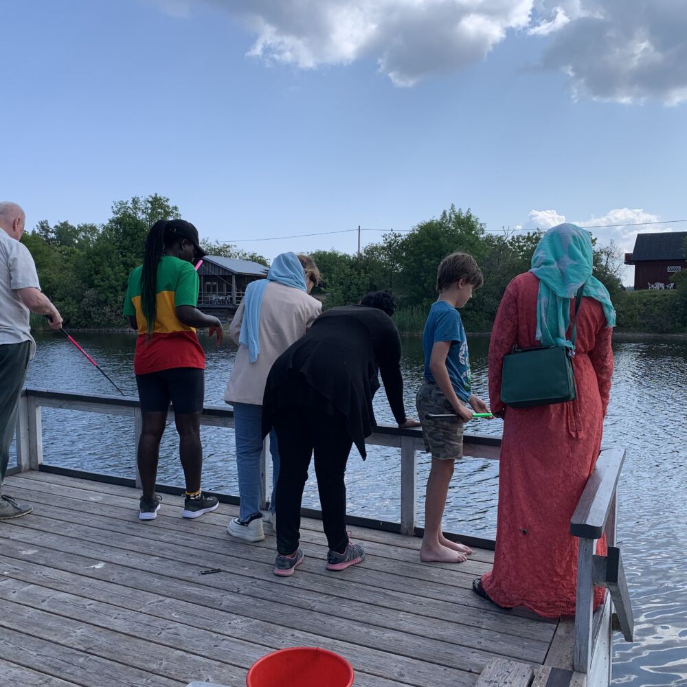 En grupp med personer står och metar på en brygga.