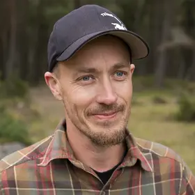 En man som heter Nicklas Johansson står med skog bakom sig.