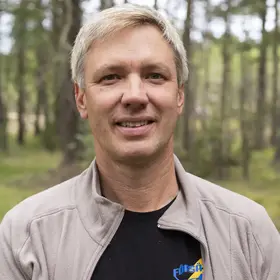 En man som heter Johan Eriksson står i en barrskog.