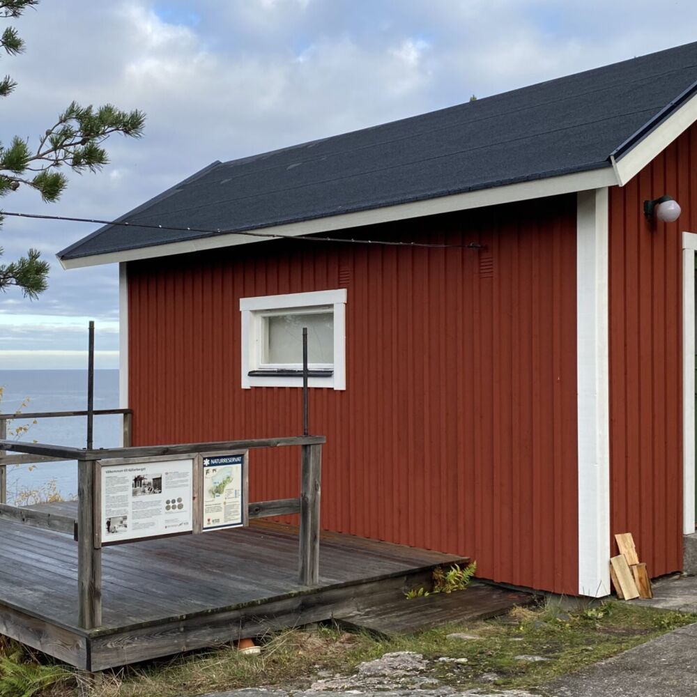 En stuga ligger på en klippa med utsikt över havet.