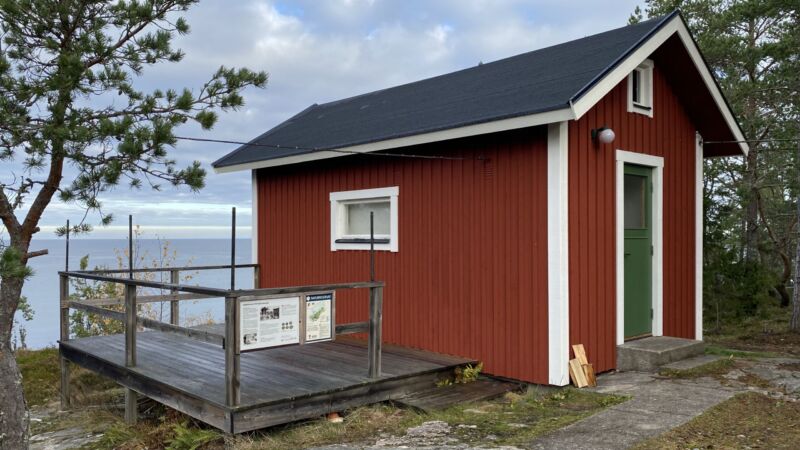 En stuga ligger på en klippa med utsikt över havet.