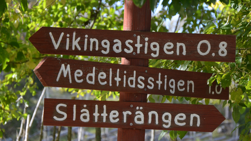 Röda skyltar med vit text som pekar ut riktningen för olika platser.
