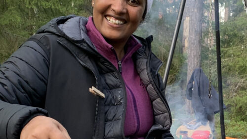 Mörkhyad kvinna lagar mat ute.