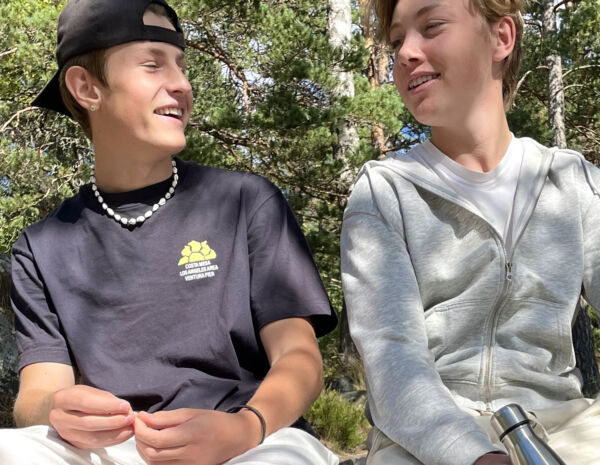 Två pojkar sitter på en sten i skogen
