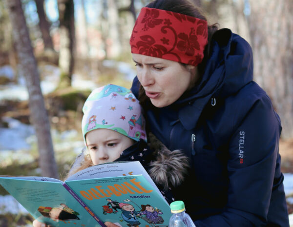 Kvinna och barn är utomhus och läser en bok