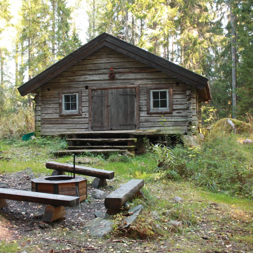 Stuga i skogen med rastplats framför