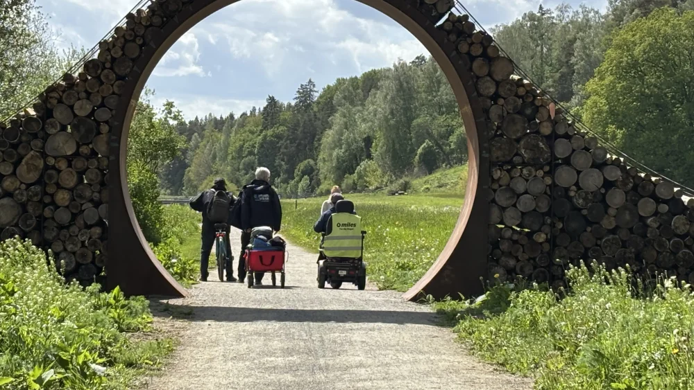 En grupp personer går och rullar med rullstol på en grusväg i Gröngarnåsen-Dyarnas naturreservat