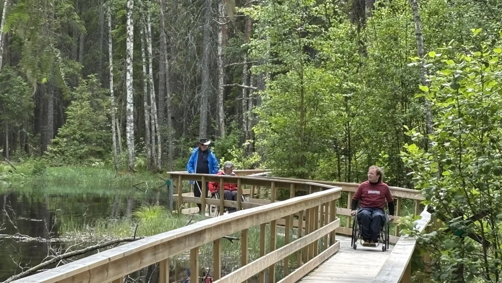En man rullar på en trätrottoar längs vattnet vid Ingbo källor.