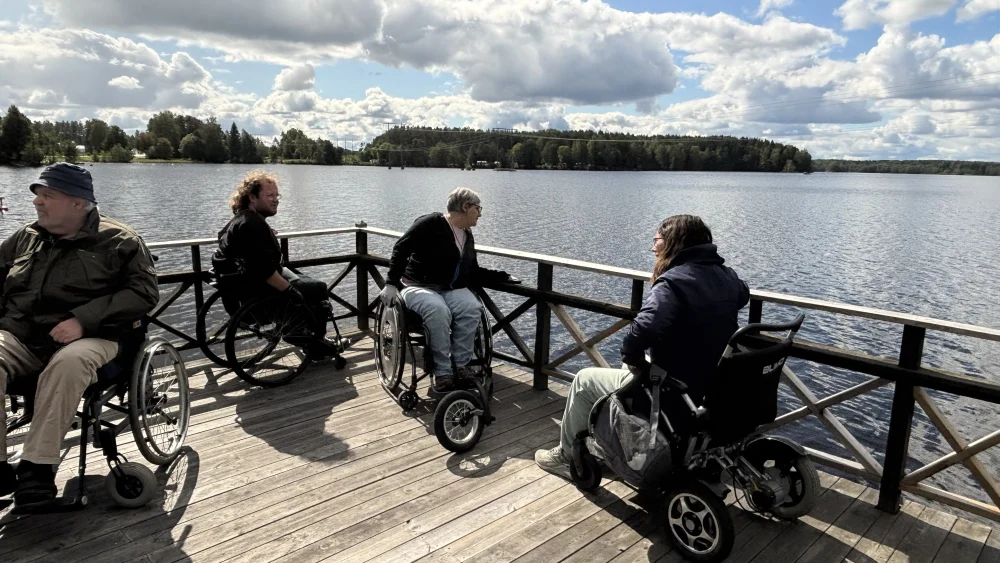 En grupp personer i rullstol njuter av Marmafjärdens utsikt från en brygga