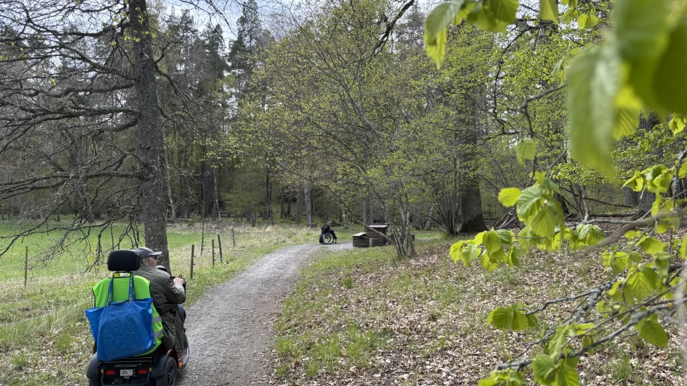 En person åker rullstol på en grusväg.