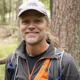 En man som är tillsynsperson i Örnsätraskogens naturreservat och heter Tomas Wärnsberg, står framför en tall i en skogen.