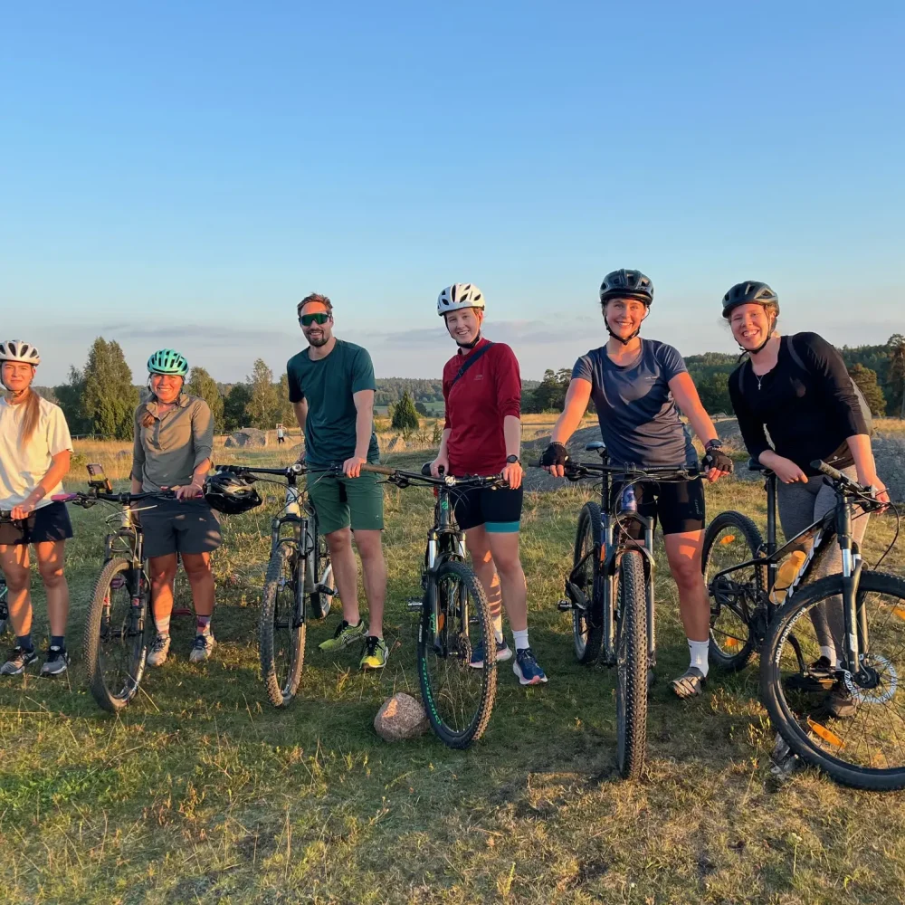 Sex personer står med sina cyklar på ett fält.